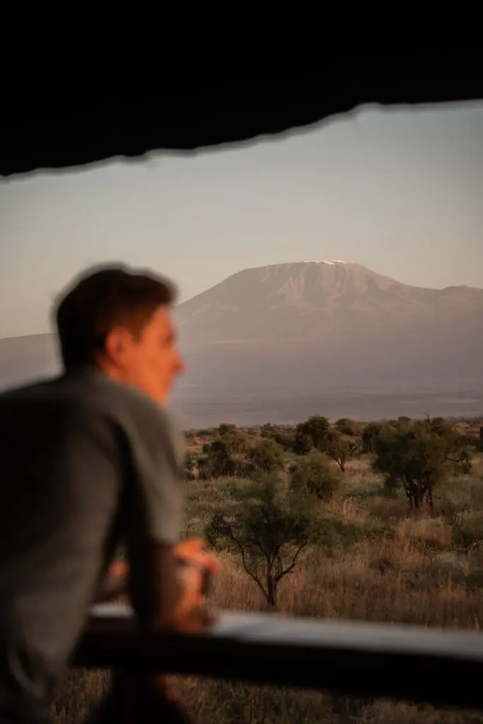 man on balcony looking at Mount Kilimanjaro at sunset