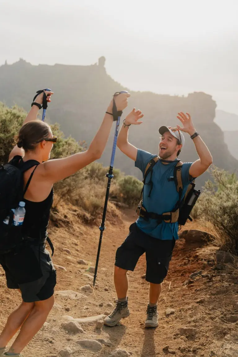 two hikers celebrating on a mountain trail at sunset